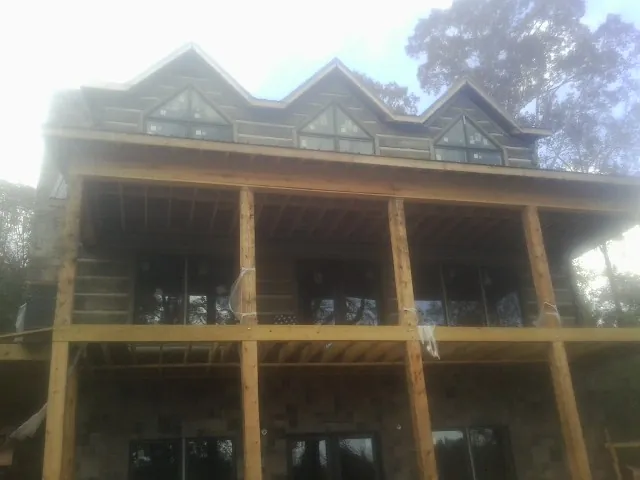 Dormers and porch framing on a large log home under construction — Roof Coating work by our crew in Burnsville
