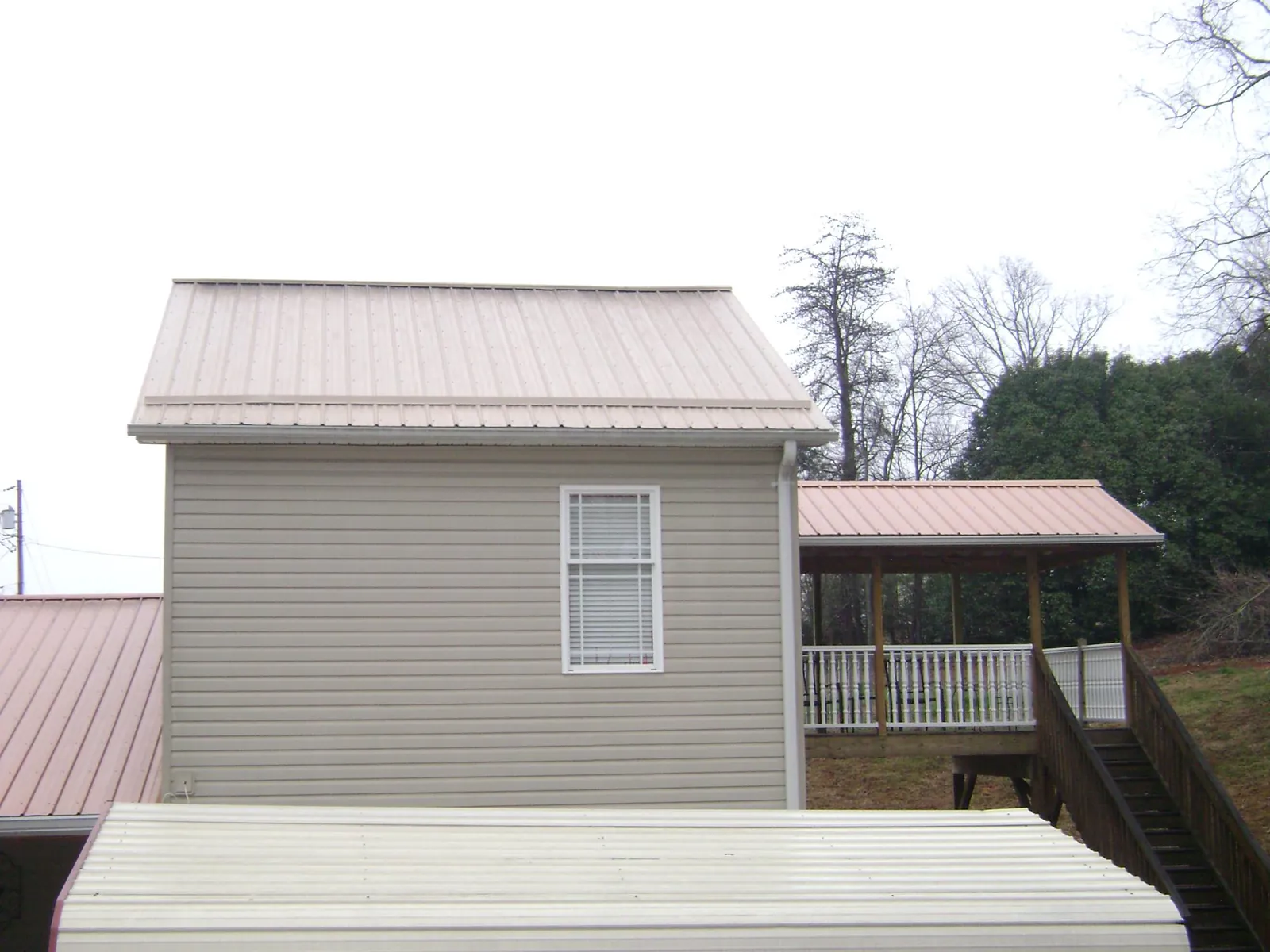 Tan metal roofs on a two story addition and attached porch, from a Roof Replacement job in Burnsville